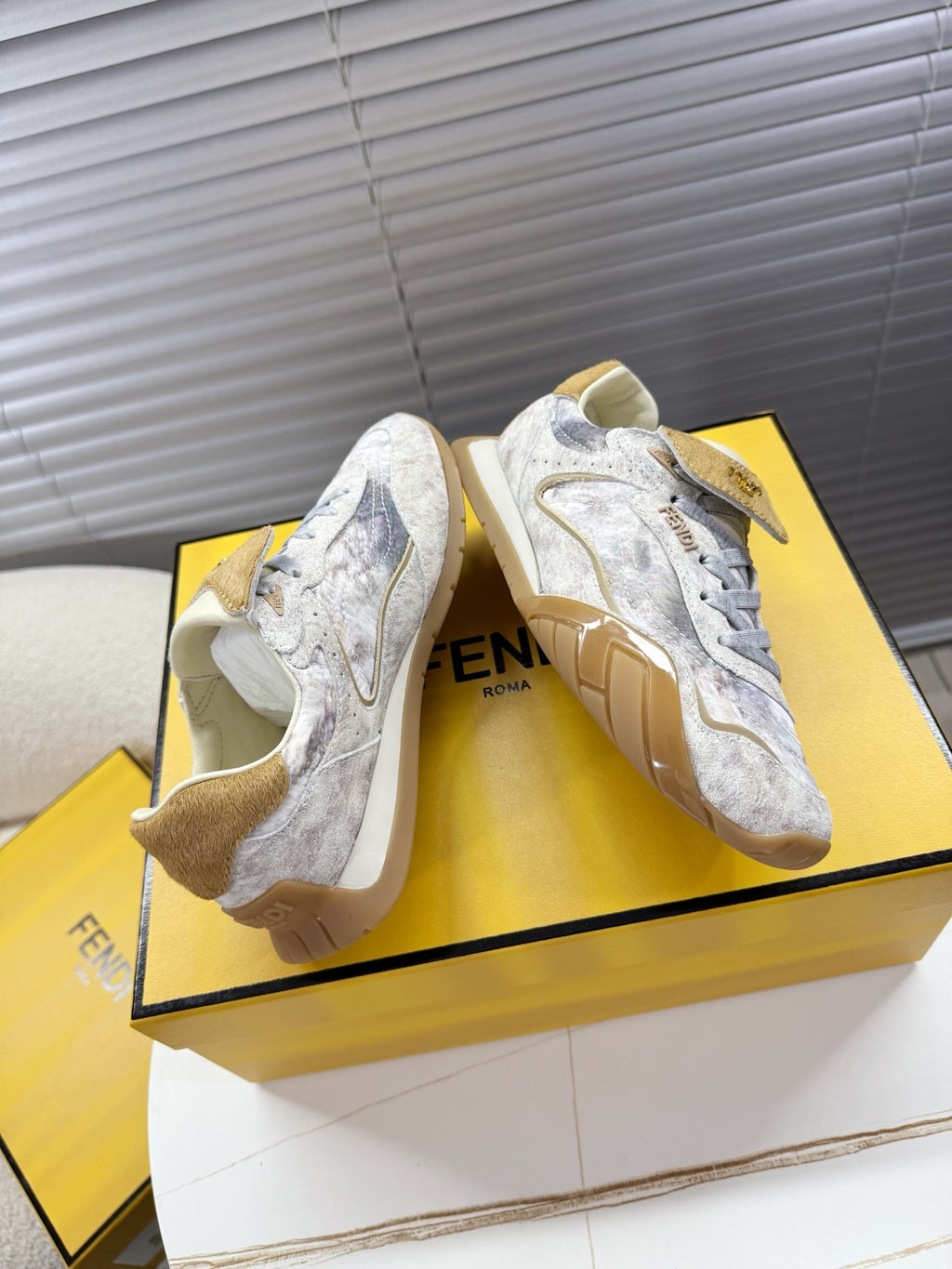 Light gray Fendi sneakers angled view with tan heel and lace-up design