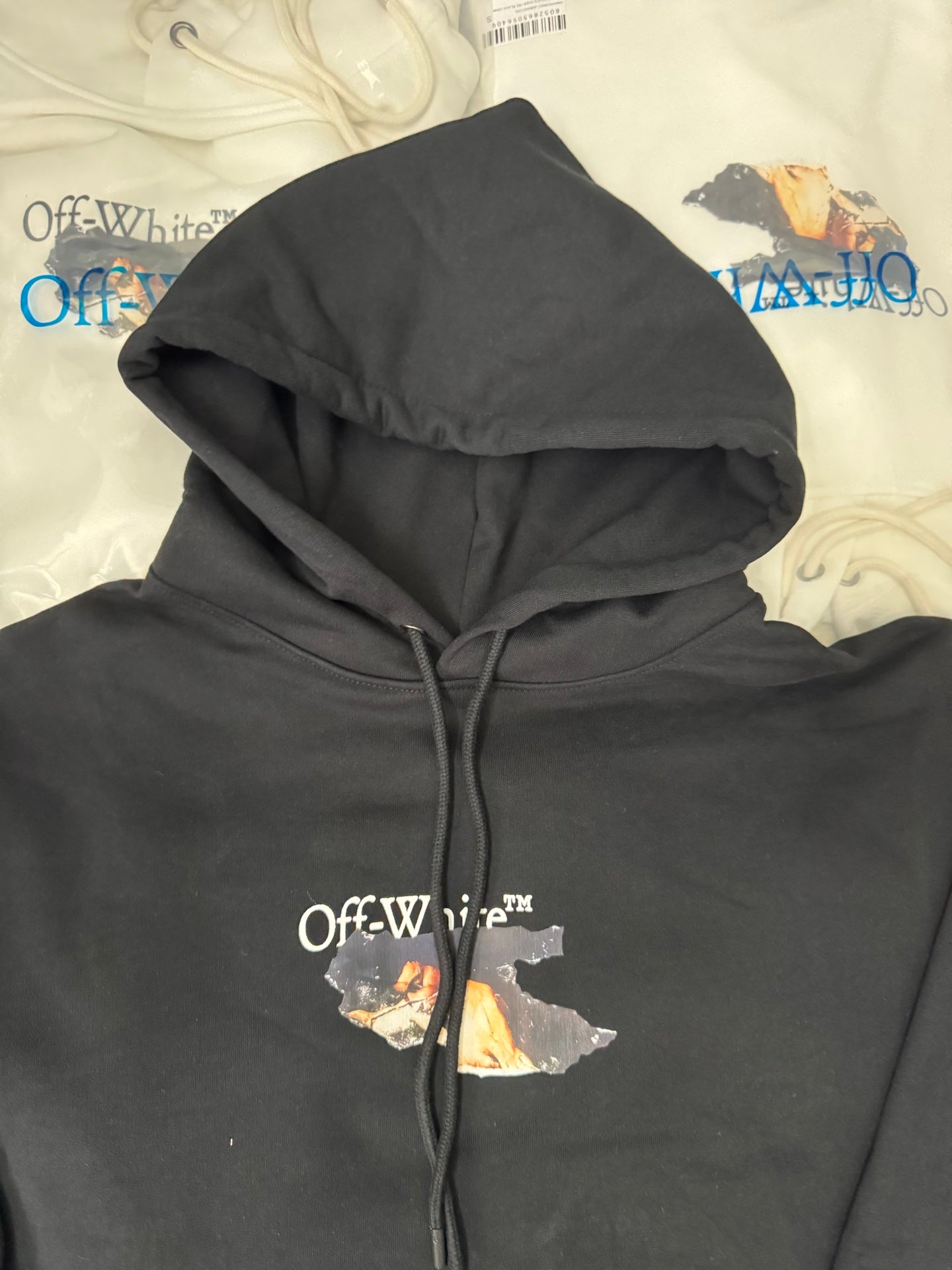 Black pullover hoodie with folded hood and front drawstring; chest graphic print