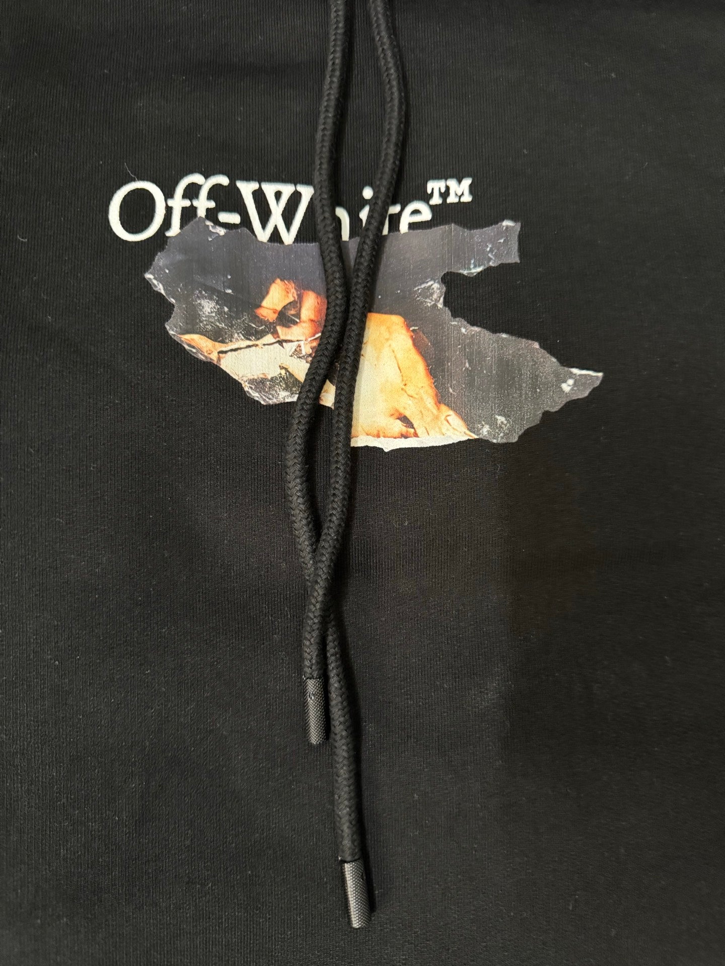 Black hoodie front close-up with Off-White logo text and graphic patch over the drawcords