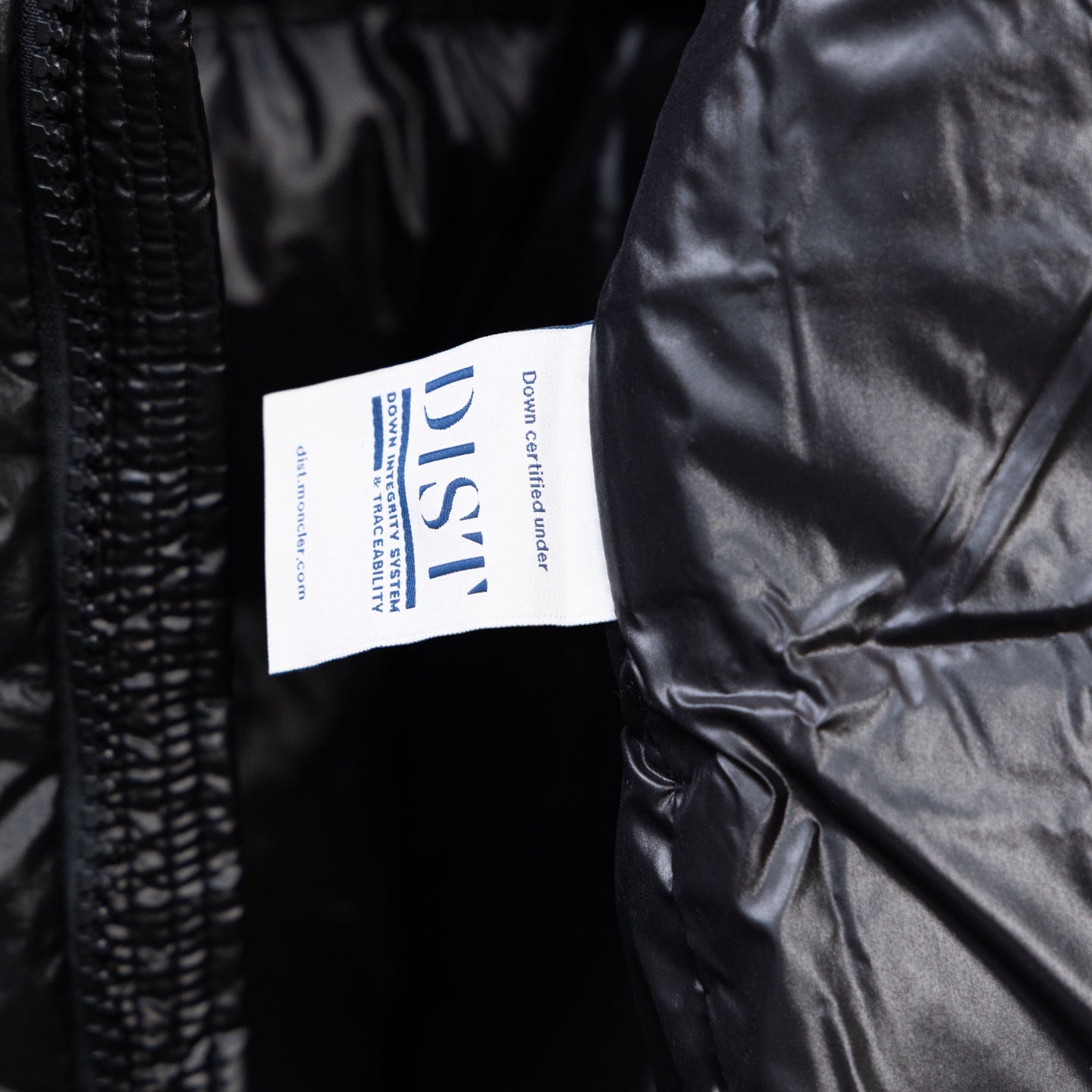 Long puffer jacket label and black glossy fabric panel detail