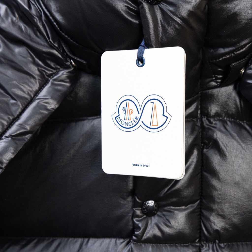 Moncler dark puffer jacket close-up, logo tag on buttoned chest pocket