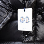 Moncler dark puffer jacket close-up, logo tag on buttoned chest pocket