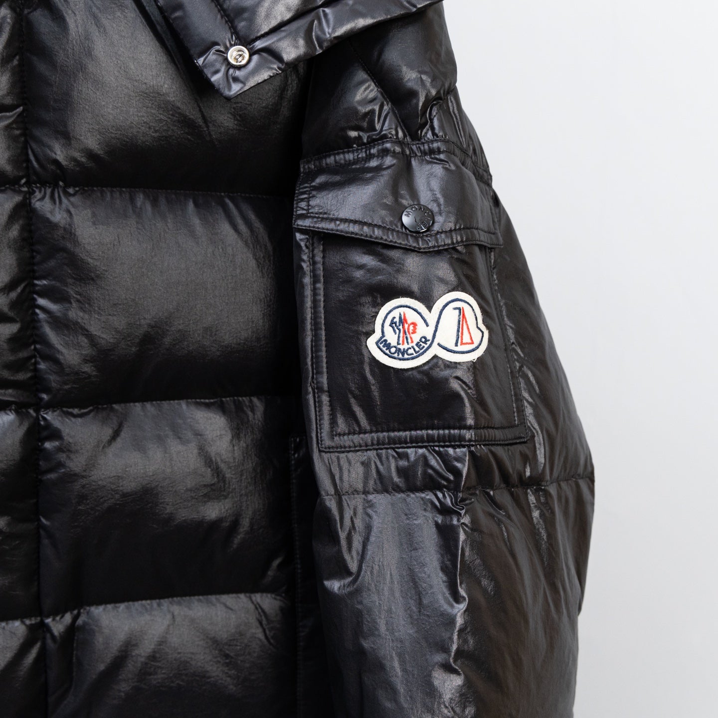 Moncler dark puffer jacket side view with chest pocket and button tabs