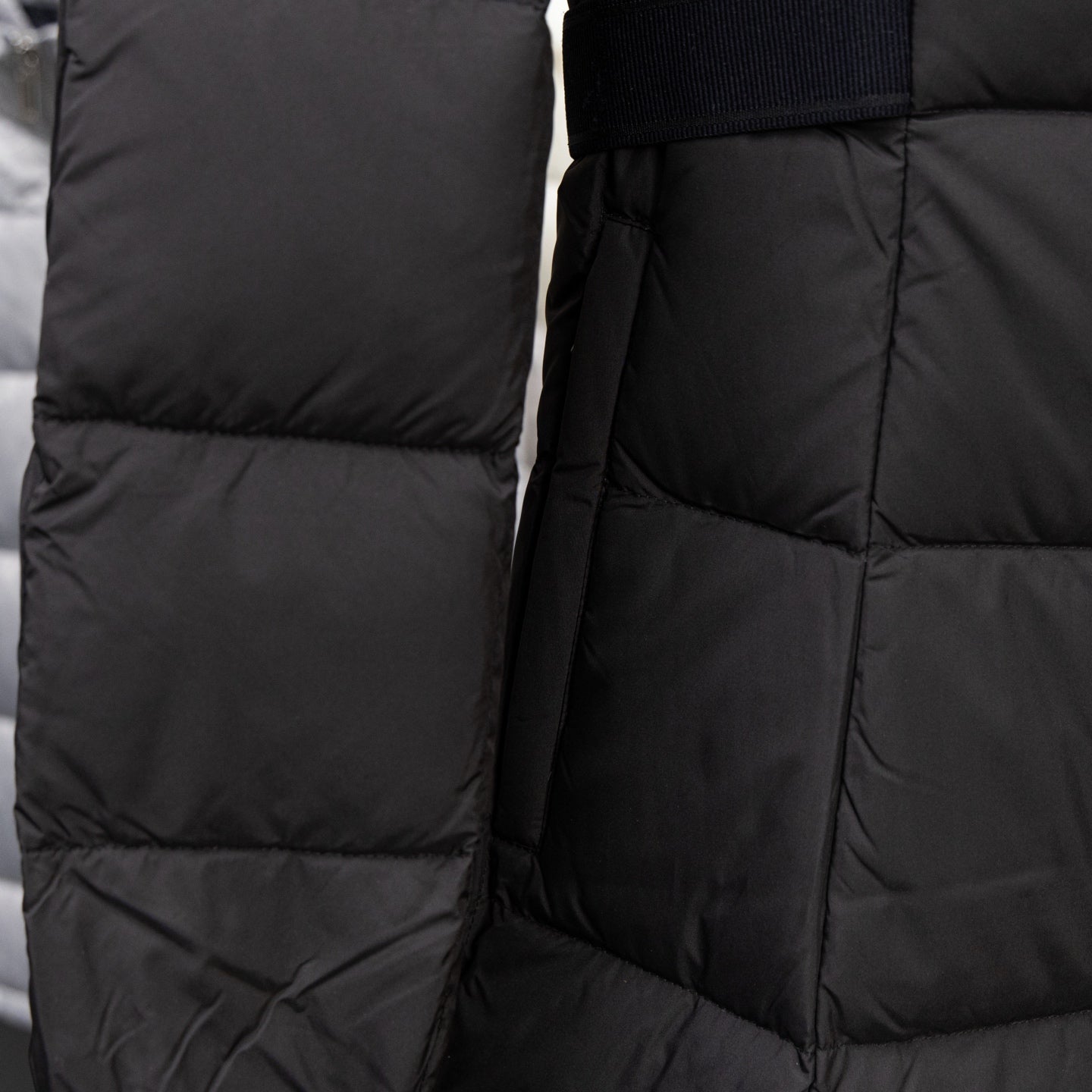 Long black puffer jacket with quilted panels and zip front