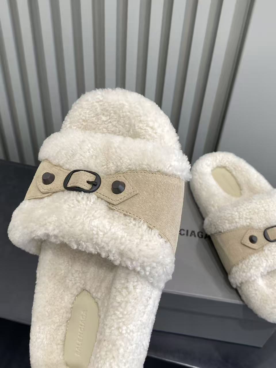 Cream sherpa slide sandals with tan strap and oval black buckle, front view