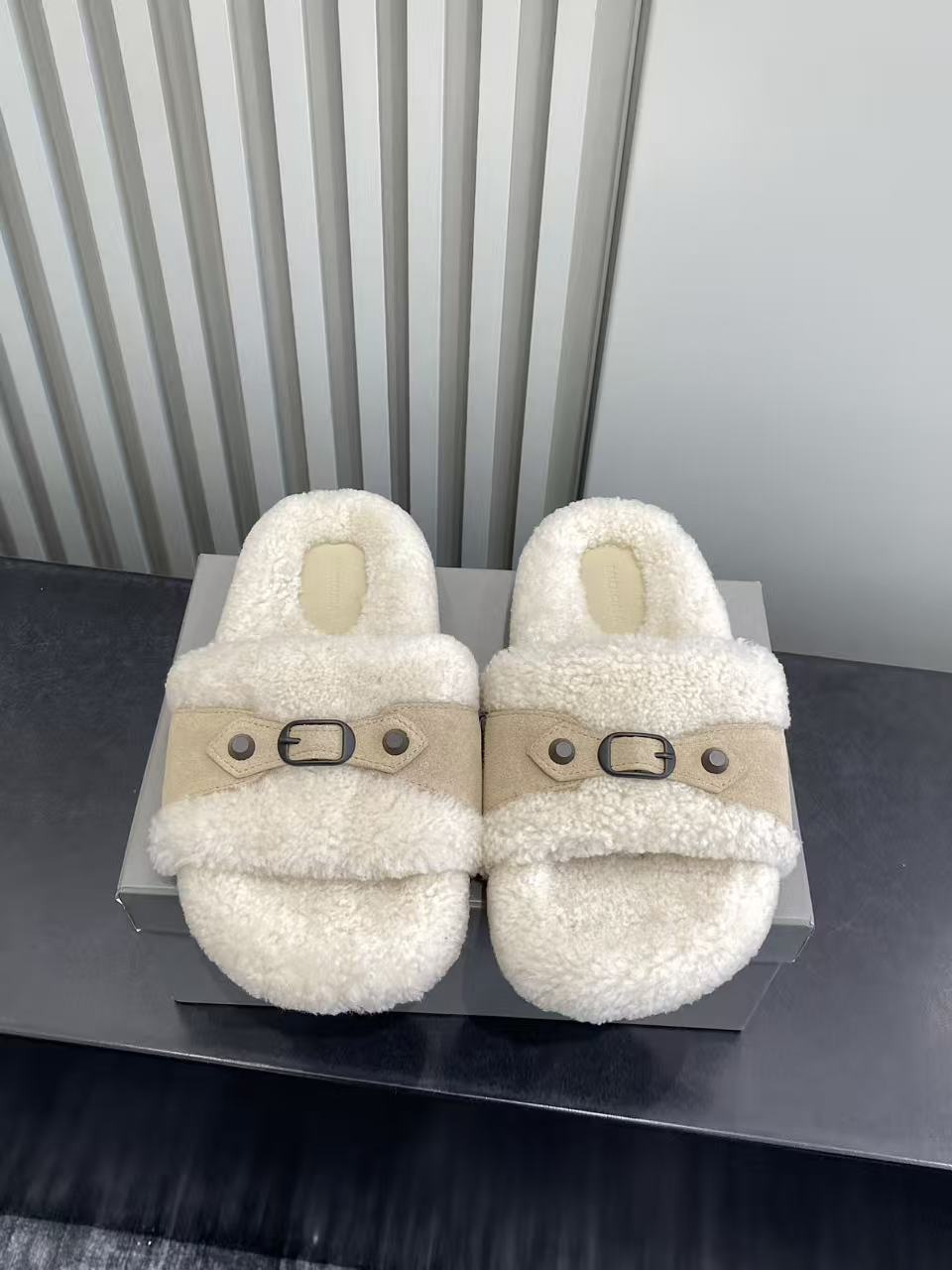 Cream fluffy slide sandals with tan cross strap and metal buckle, pair front view