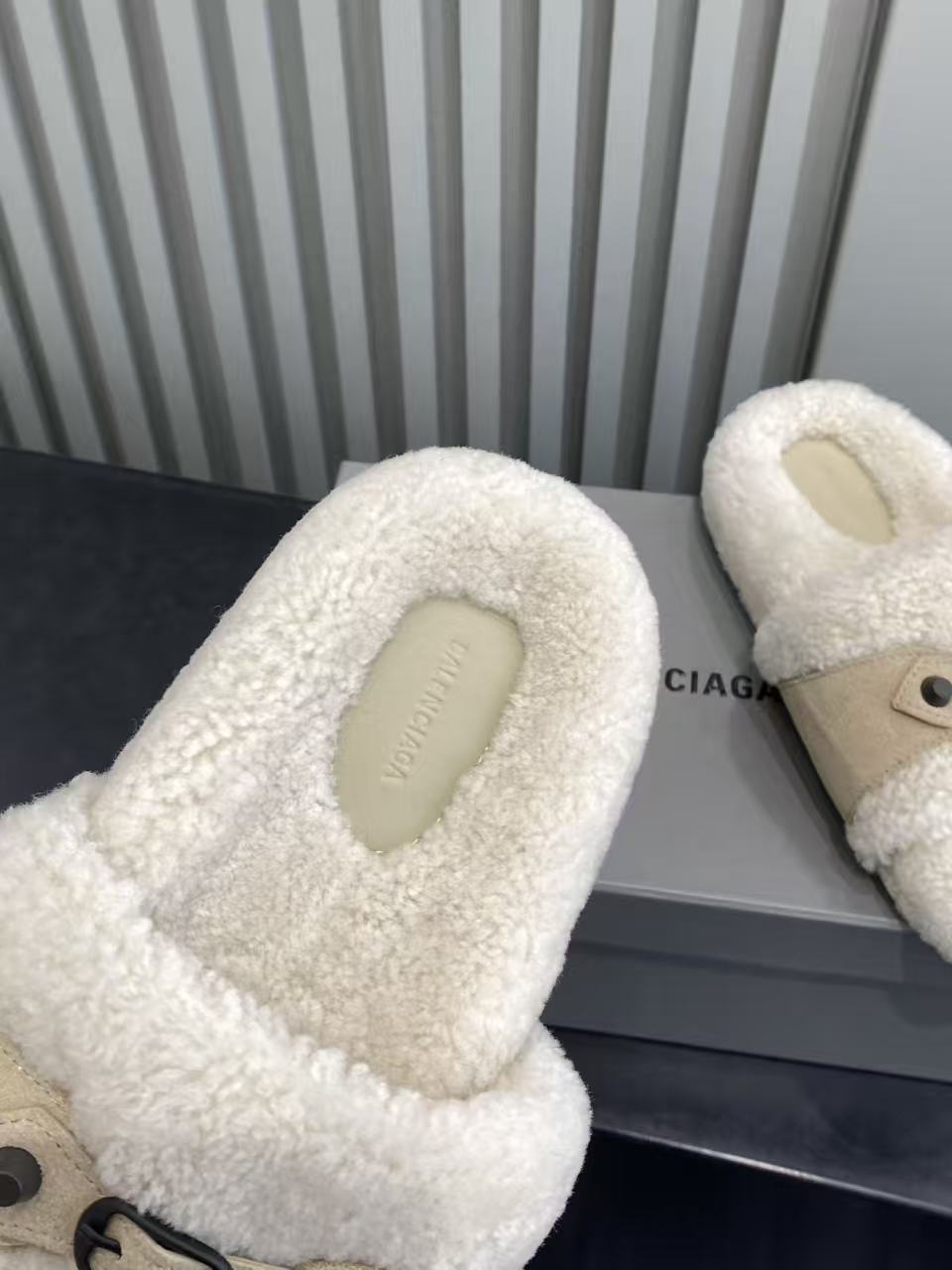 Cream sherpa slide sandal with open toe cutout and tan strap, angled view