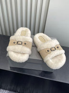 Cream fuzzy slide sandals with tan strap and black buckle, pair side-by-side