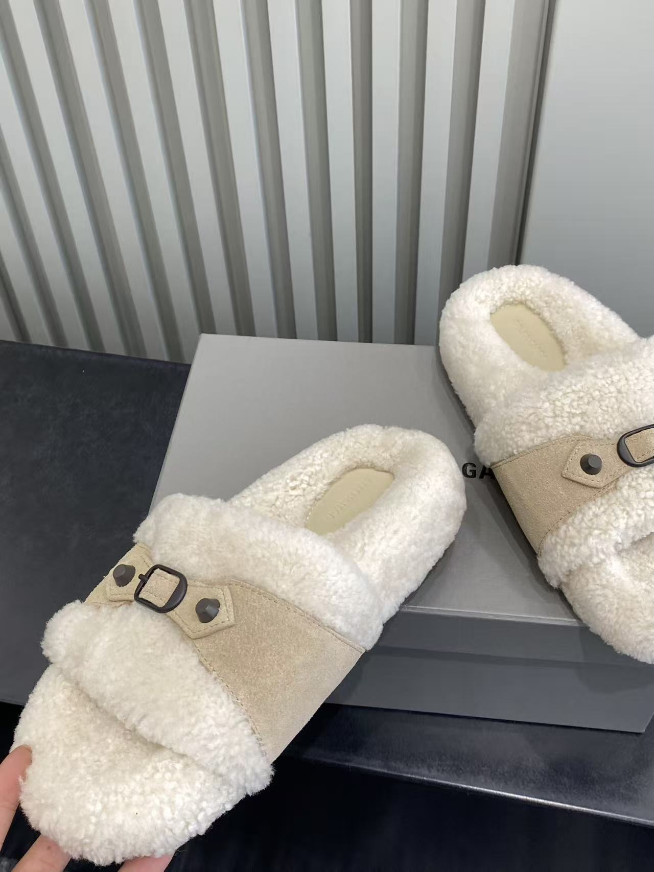 Cream sherpa slide sandals with tan strap and black buckle, side view