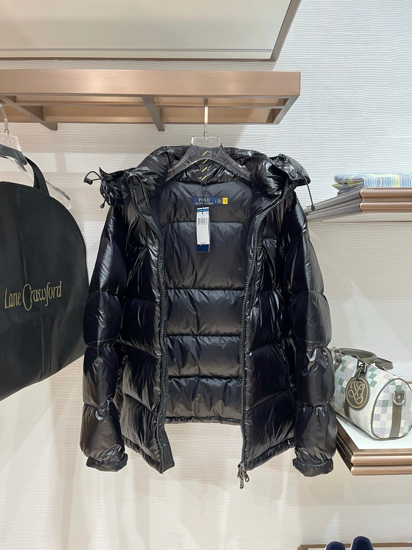 Black hooded puffer jacket with zip front, quilted panels, and hanging tag