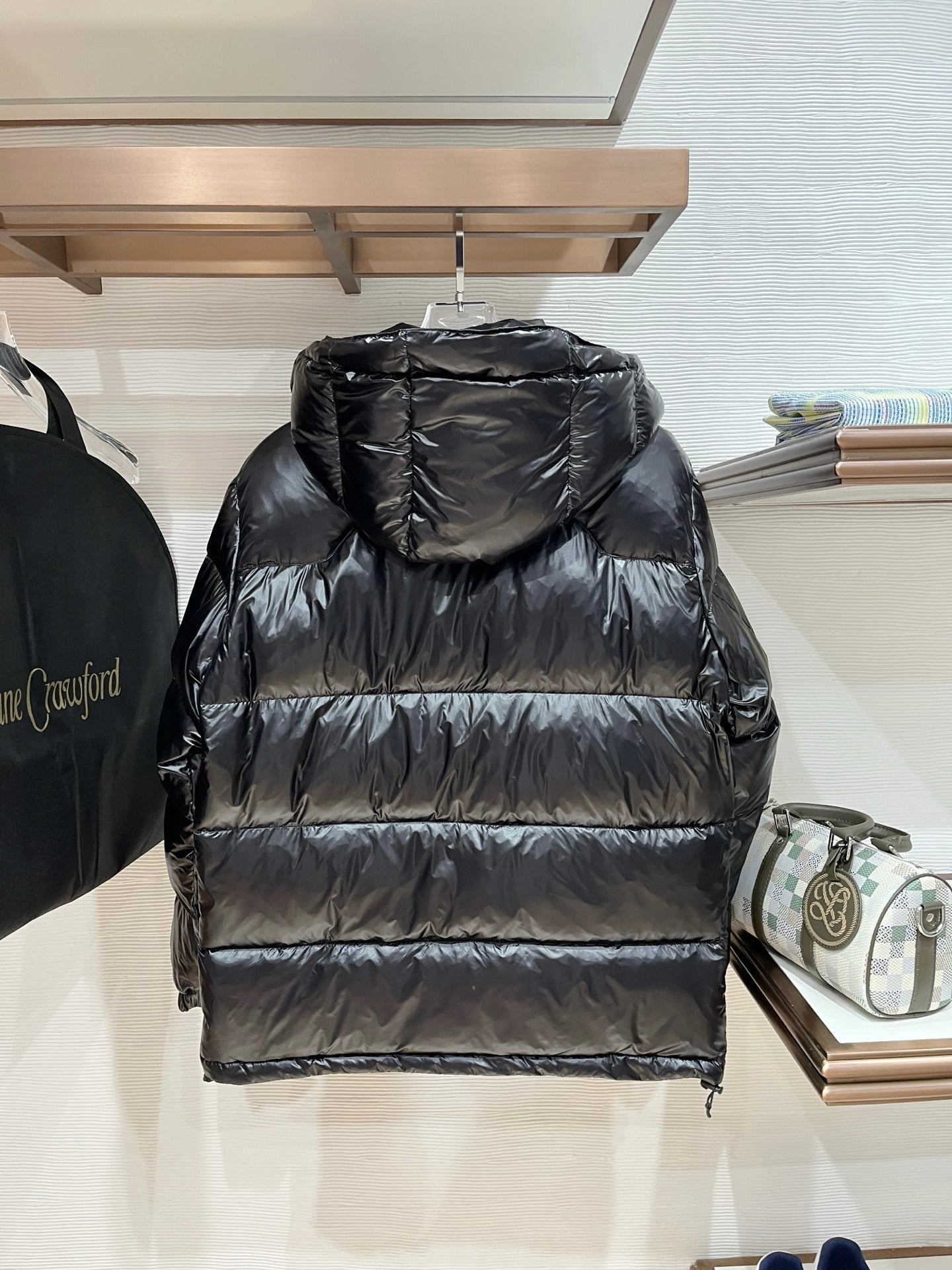 Black hooded puffer jacket with quilted stripes across the back