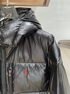Black puffer jacket with hood, quilted panels, and red polo logo on chest