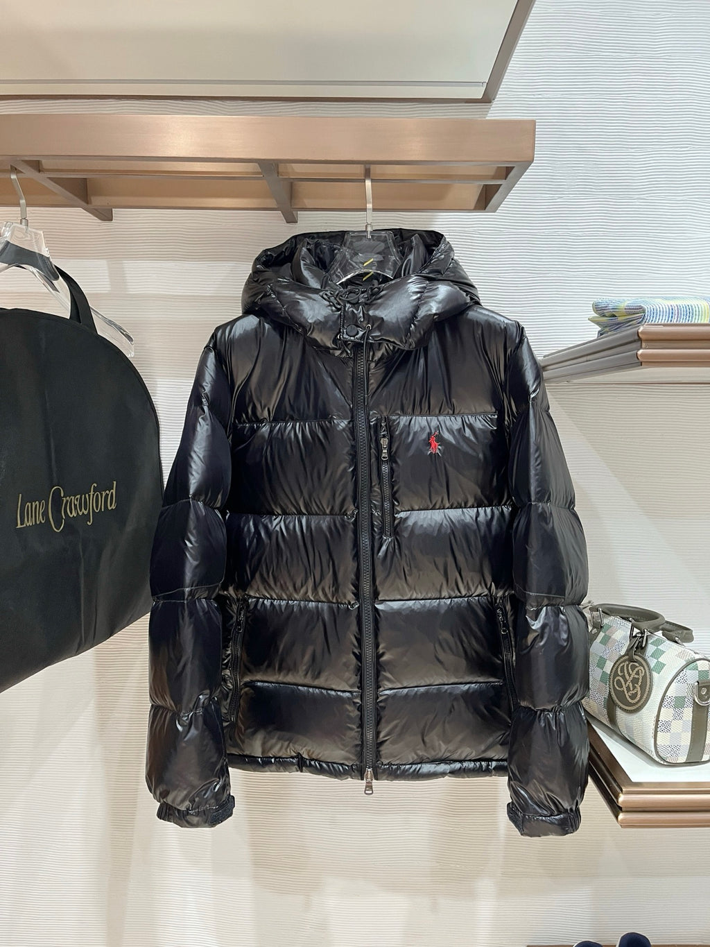 Black hooded puffer jacket with zip front and red polo logo on chest
