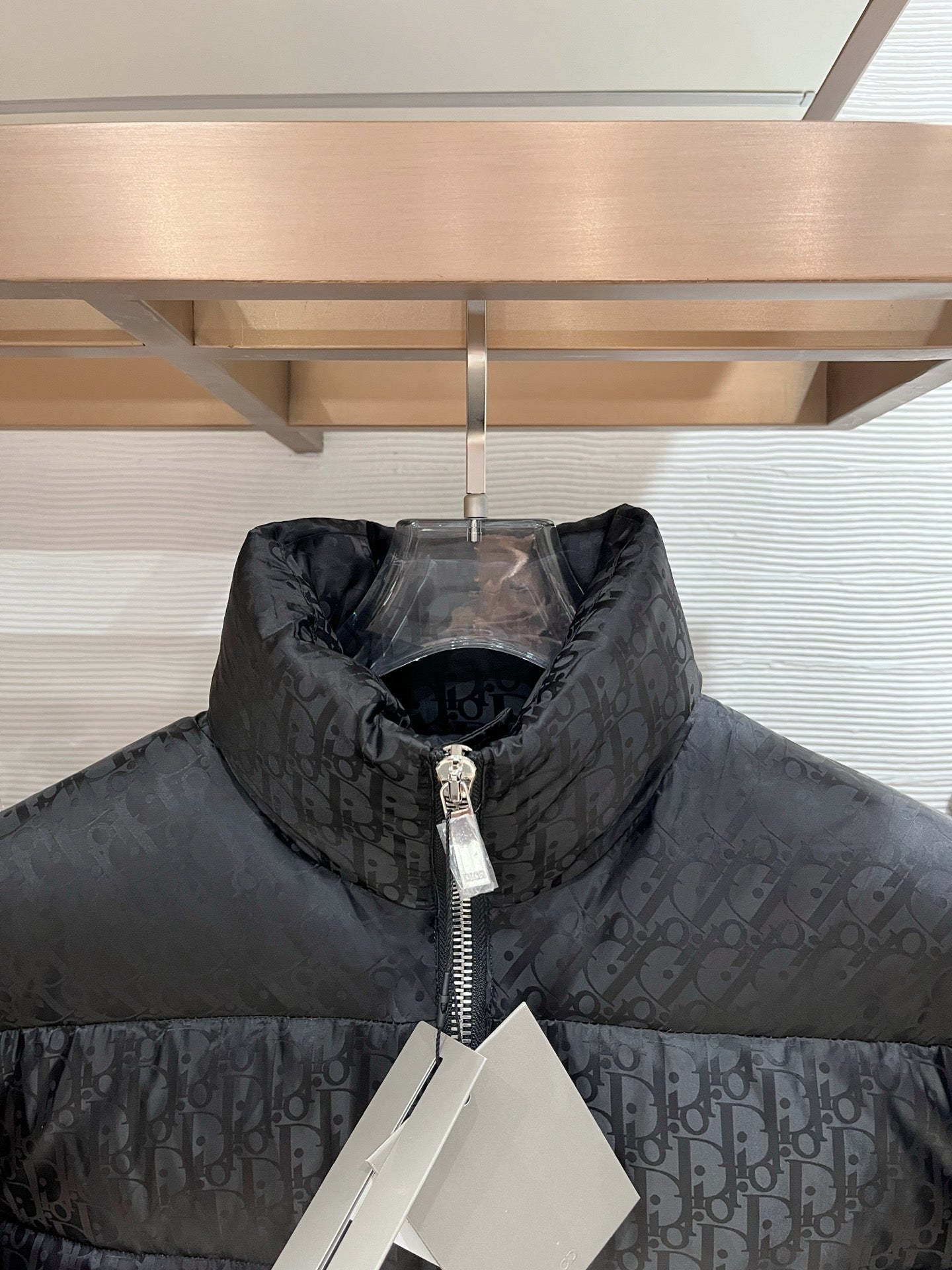 Black puffer jacket close-up with allover logo pattern and zip neckline