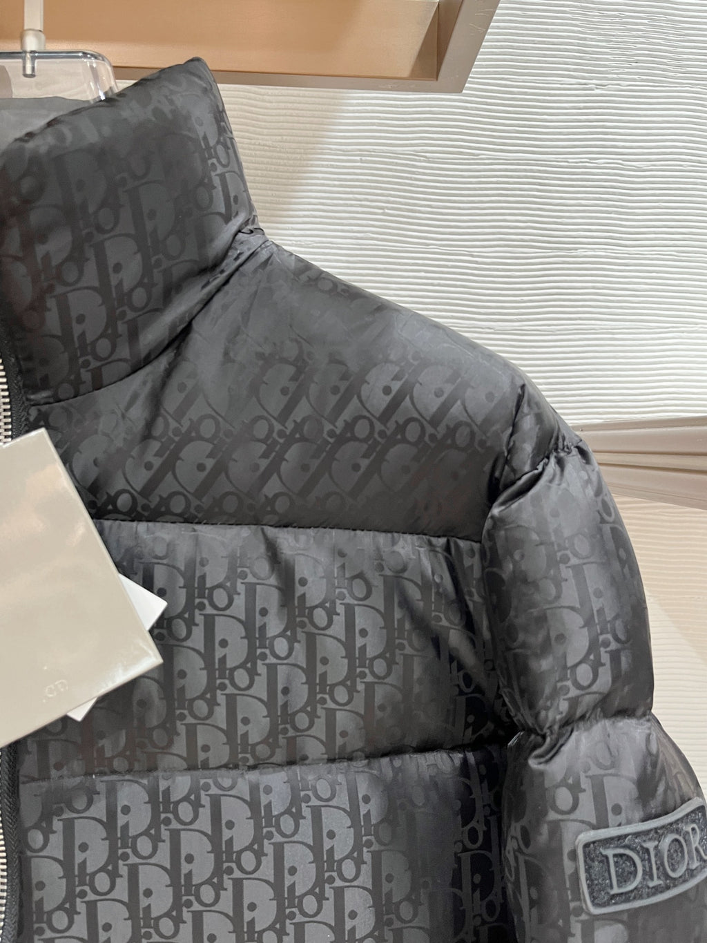 Black puffer jacket with allover logo pattern and padded shoulder
