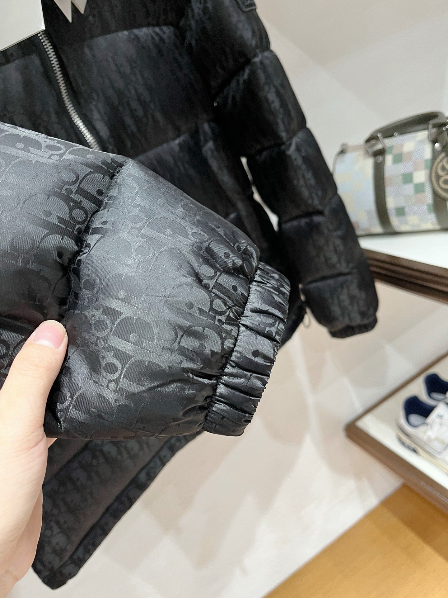 Black puffer jacket sleeve with allover logo pattern and elastic cuff