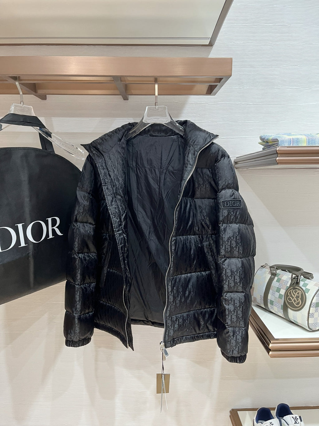 Black puffer jacket on hanger, full front view with zip
