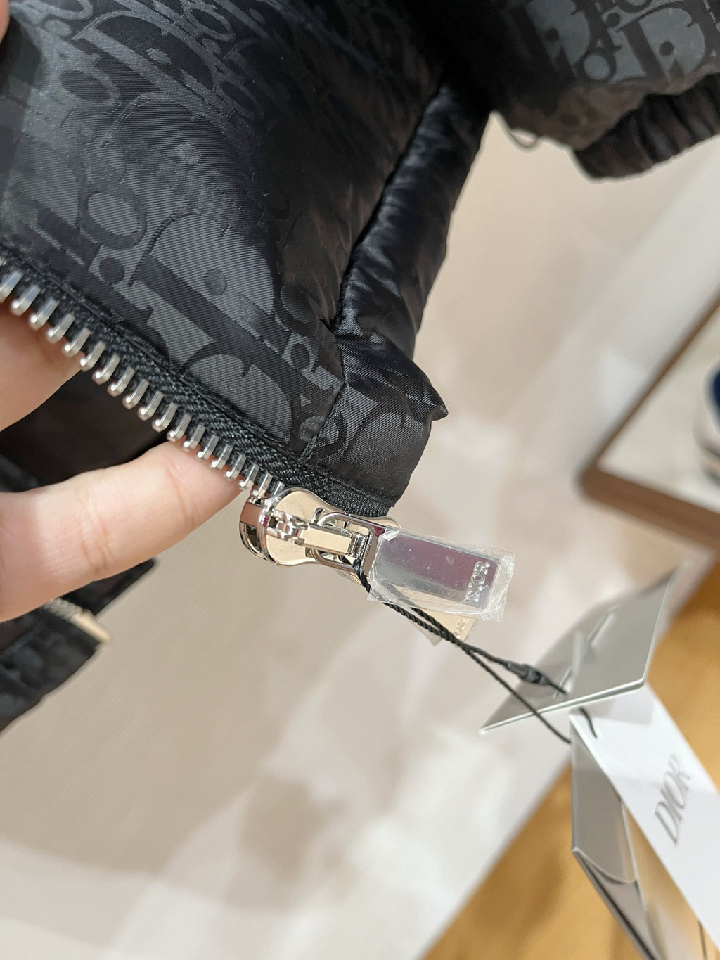 Black puffer jacket close-up of zipper pull and logo-stamped fabric
