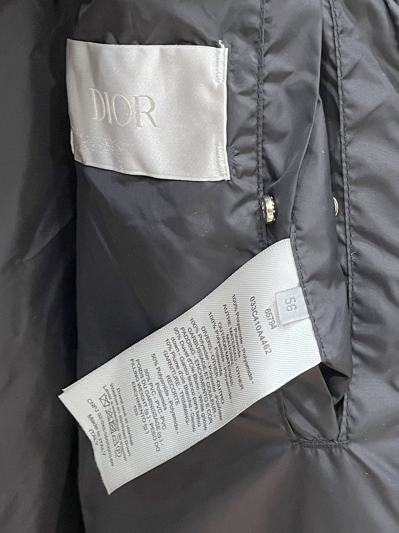 Black puffer jacket with white interior label and zip placket detail
