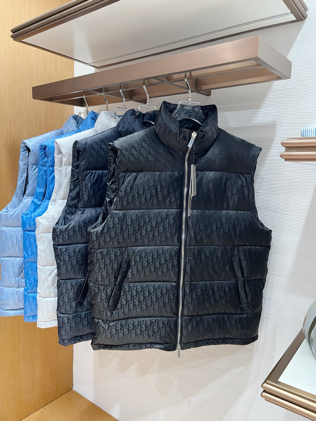 Dark quilted puffer vest with stand collar and front zipper on rack
