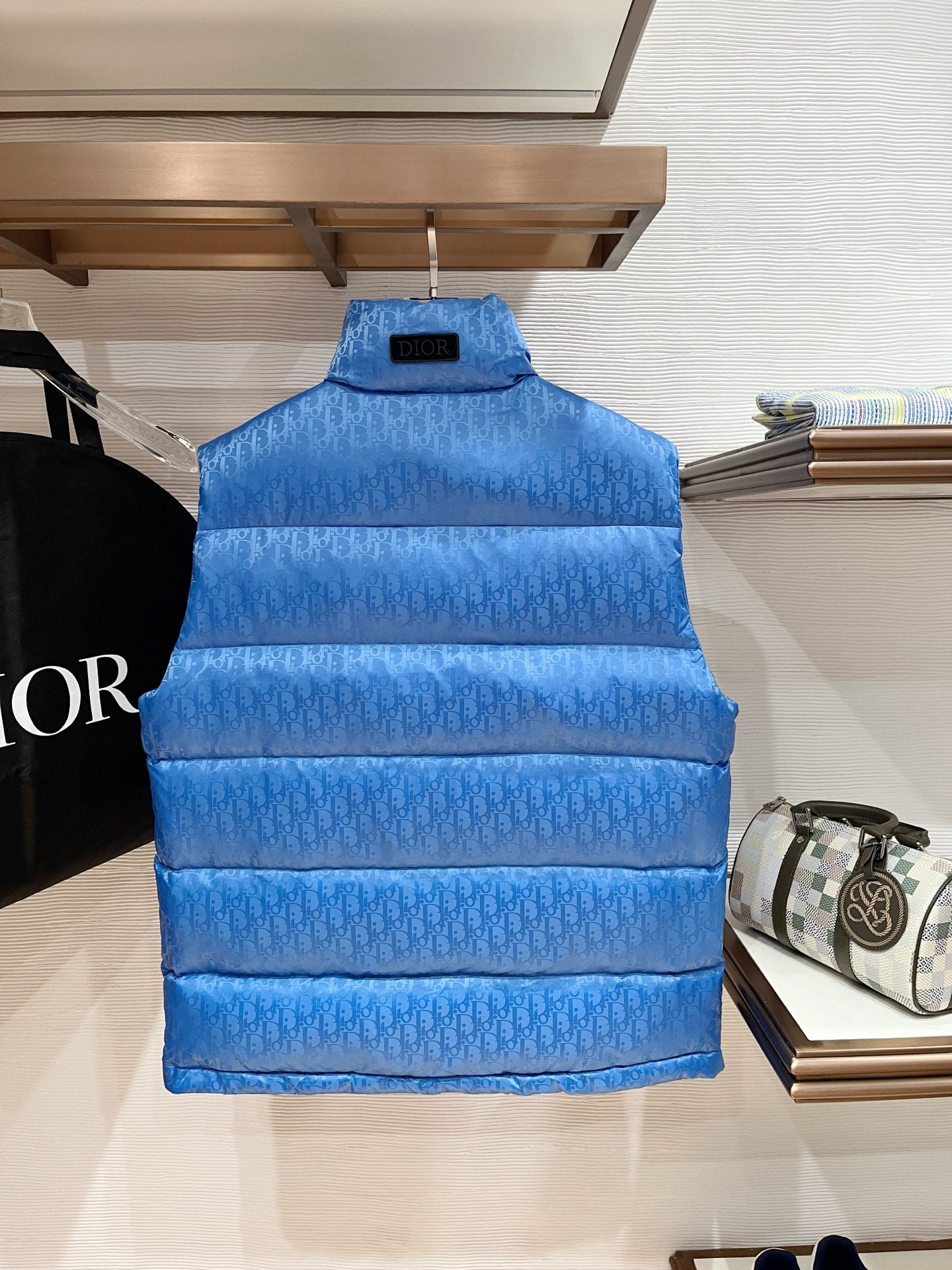 Blue quilted puffer vest on hanger with stand collar and front zipper