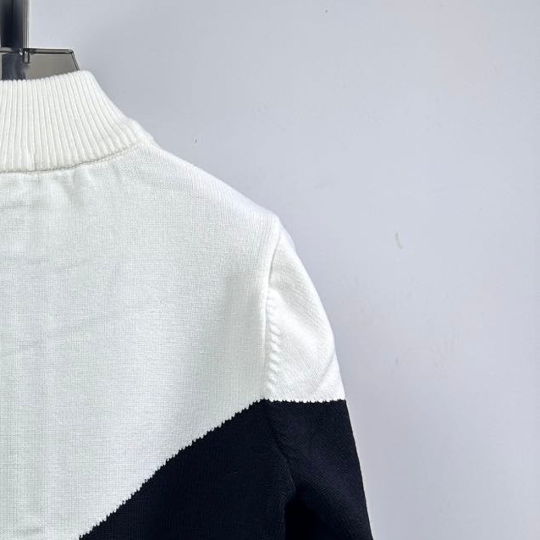 White knit zip-up sweater with ribbed turtleneck and diagonal navy panel at side