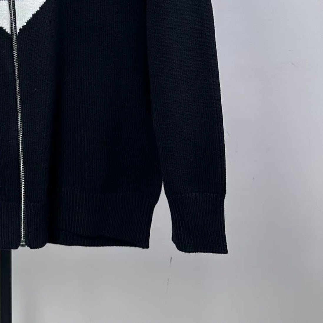 Navy knit zip-up sweater sleeve and side seam with ribbed cuff