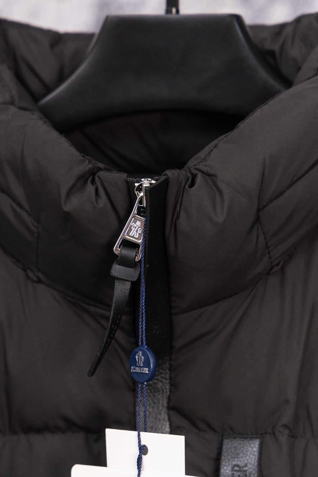 Long black puffer jacket front zipper pull with Moncler hang tag