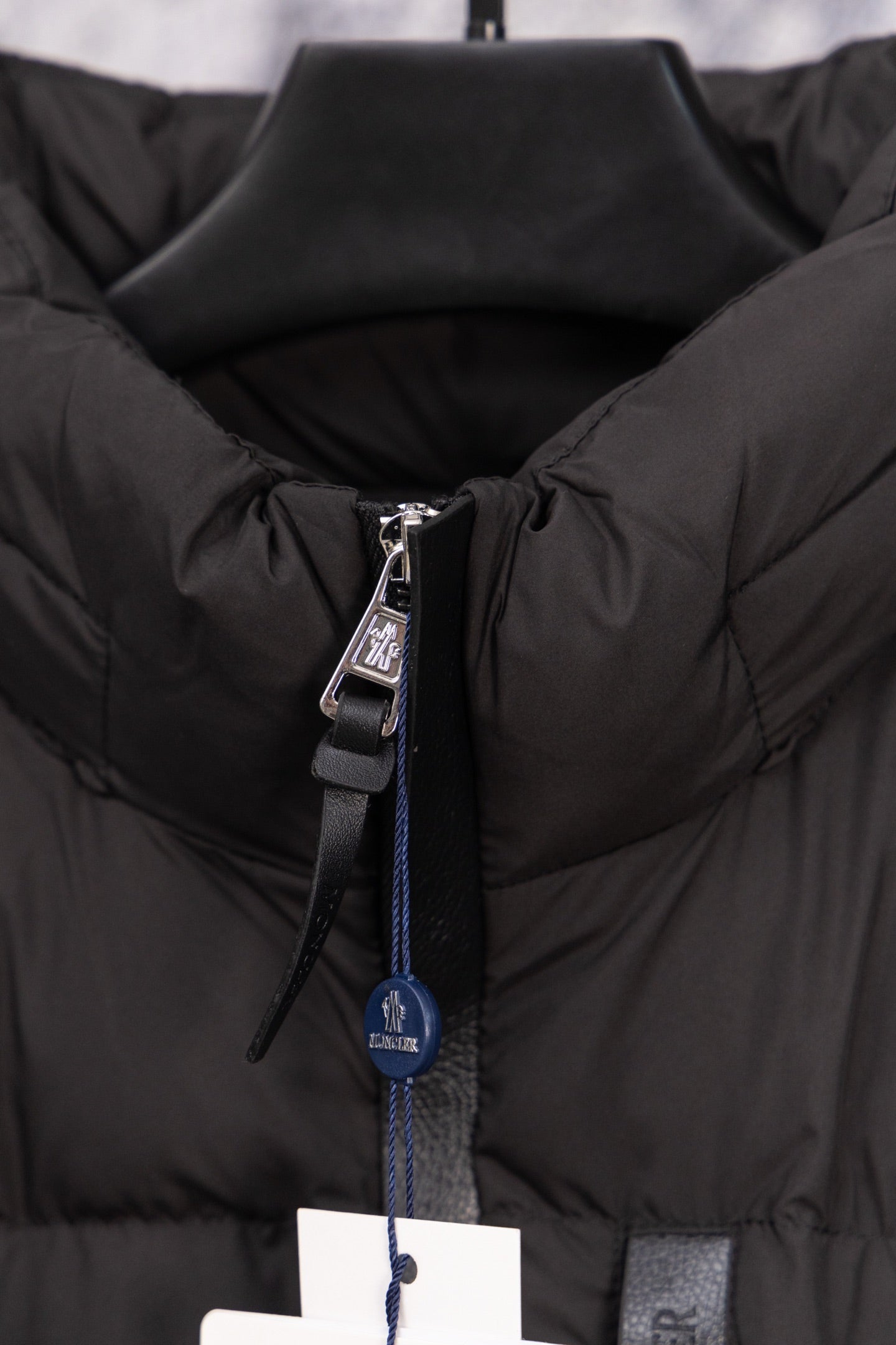 Long black puffer jacket front zipper pull with Moncler hang tag