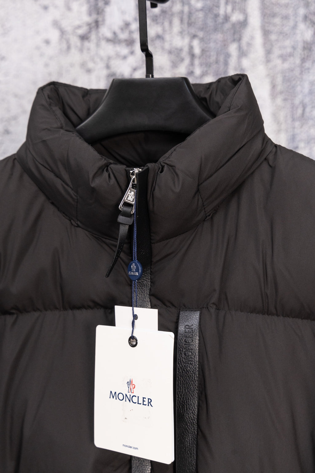 Black Moncler puffer jacket front with full zip, high collar, hanging tag