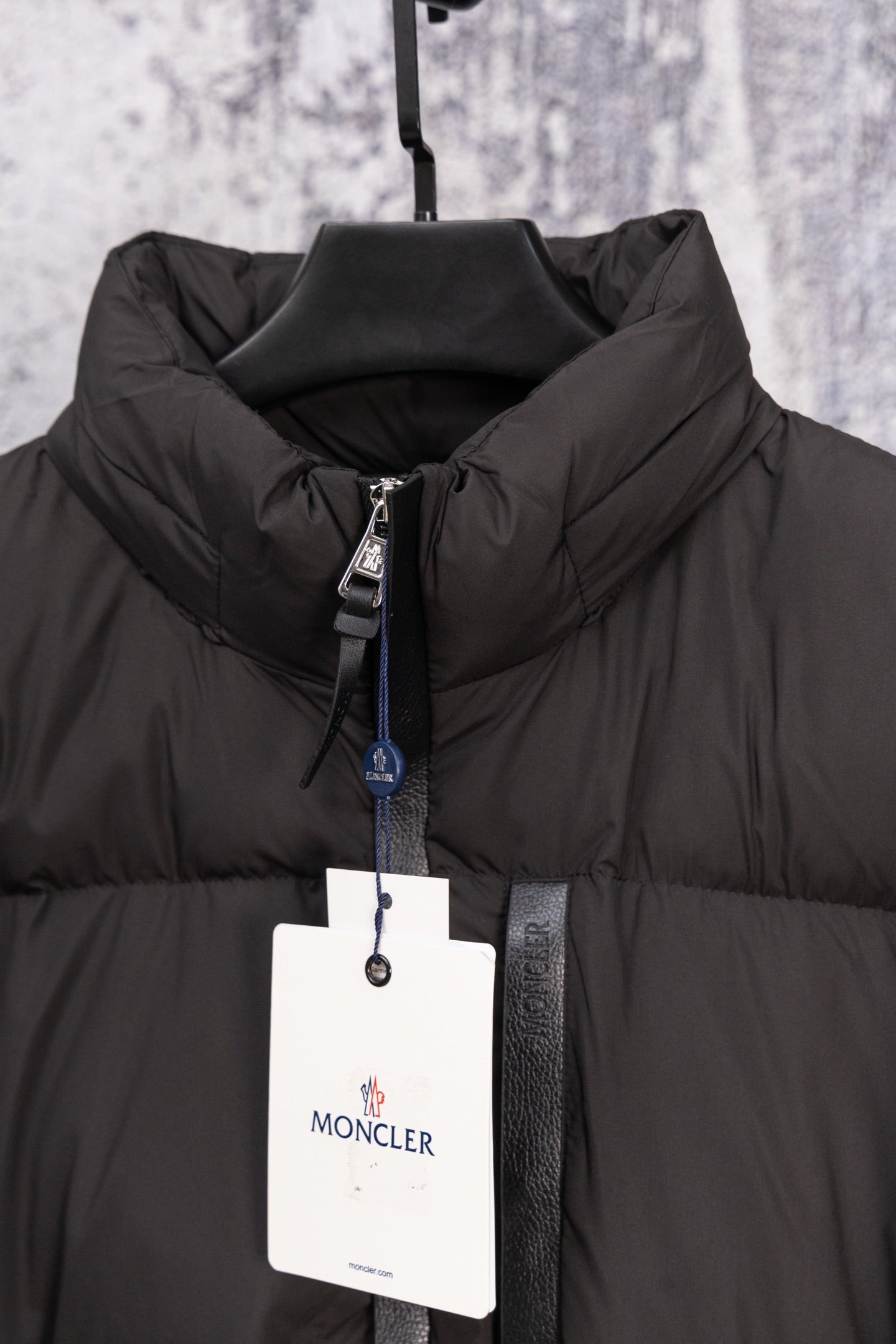 Black Moncler puffer jacket front with full zip, high collar, hanging tag