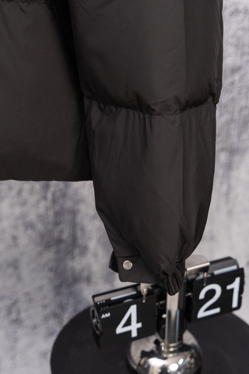 Long black puffer jacket hem with snap cuff detail