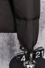 Long black puffer jacket hem with snap cuff detail