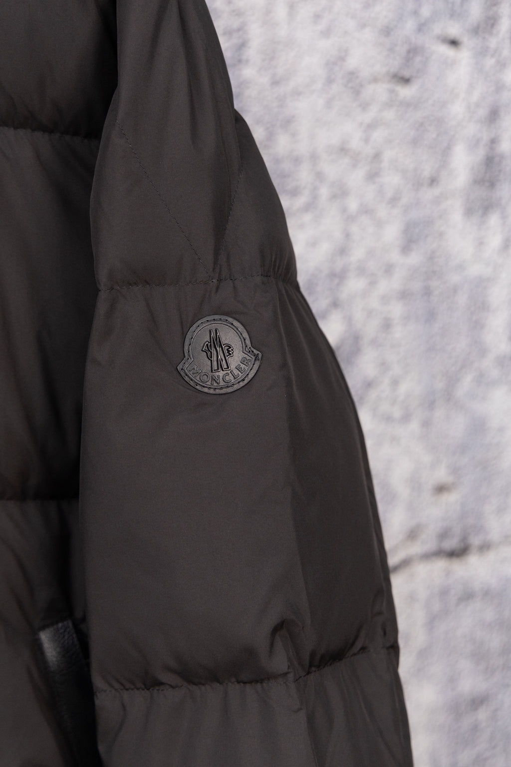 Black long puffer jacket sleeve with Moncler crest logo patch