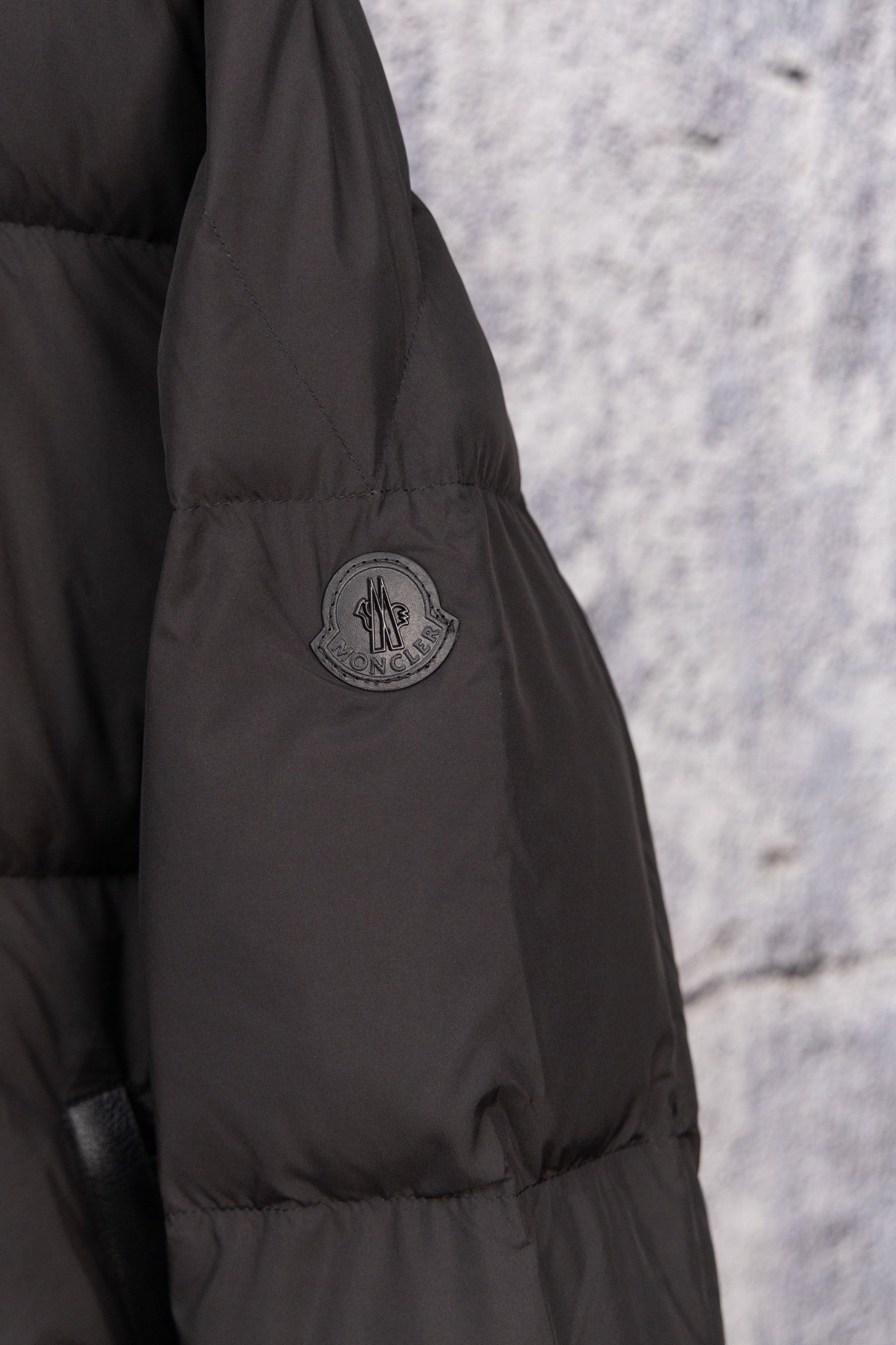 Black long puffer jacket sleeve with Moncler crest logo patch
