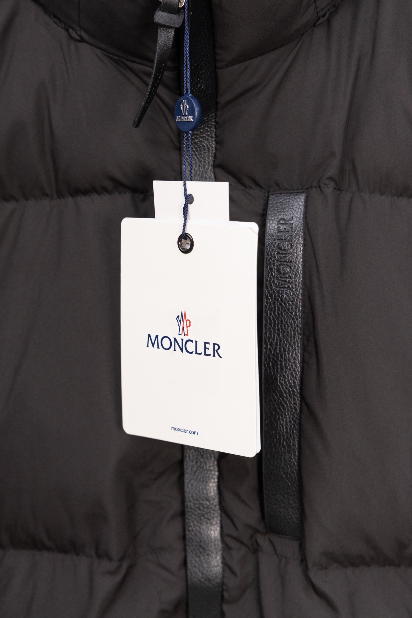 Long black puffer jacket with Moncler logo hanging tag