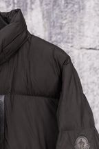 Long black puffer jacket shoulder seam with circular logo patch
