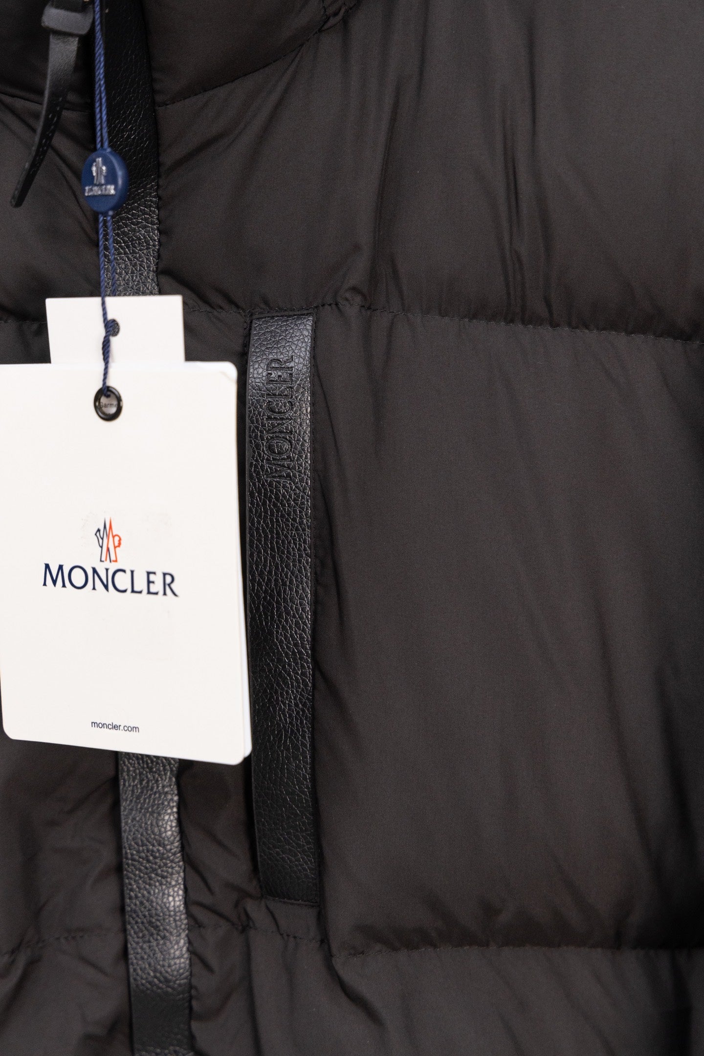 Long black puffer jacket pocket area with Moncler logo tag