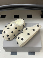 Cream polka-dot clogs with shearling lining on light box, side and front view