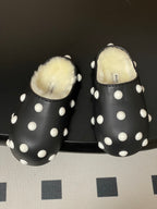 Black slide sandals with white polka dots and fluffy interior shearling lining.