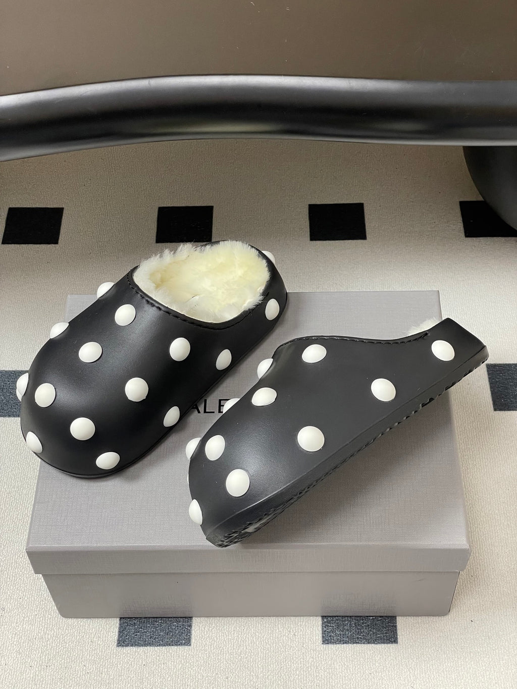 Black polka-dot slide clogs with white dots and plush shearling lining.