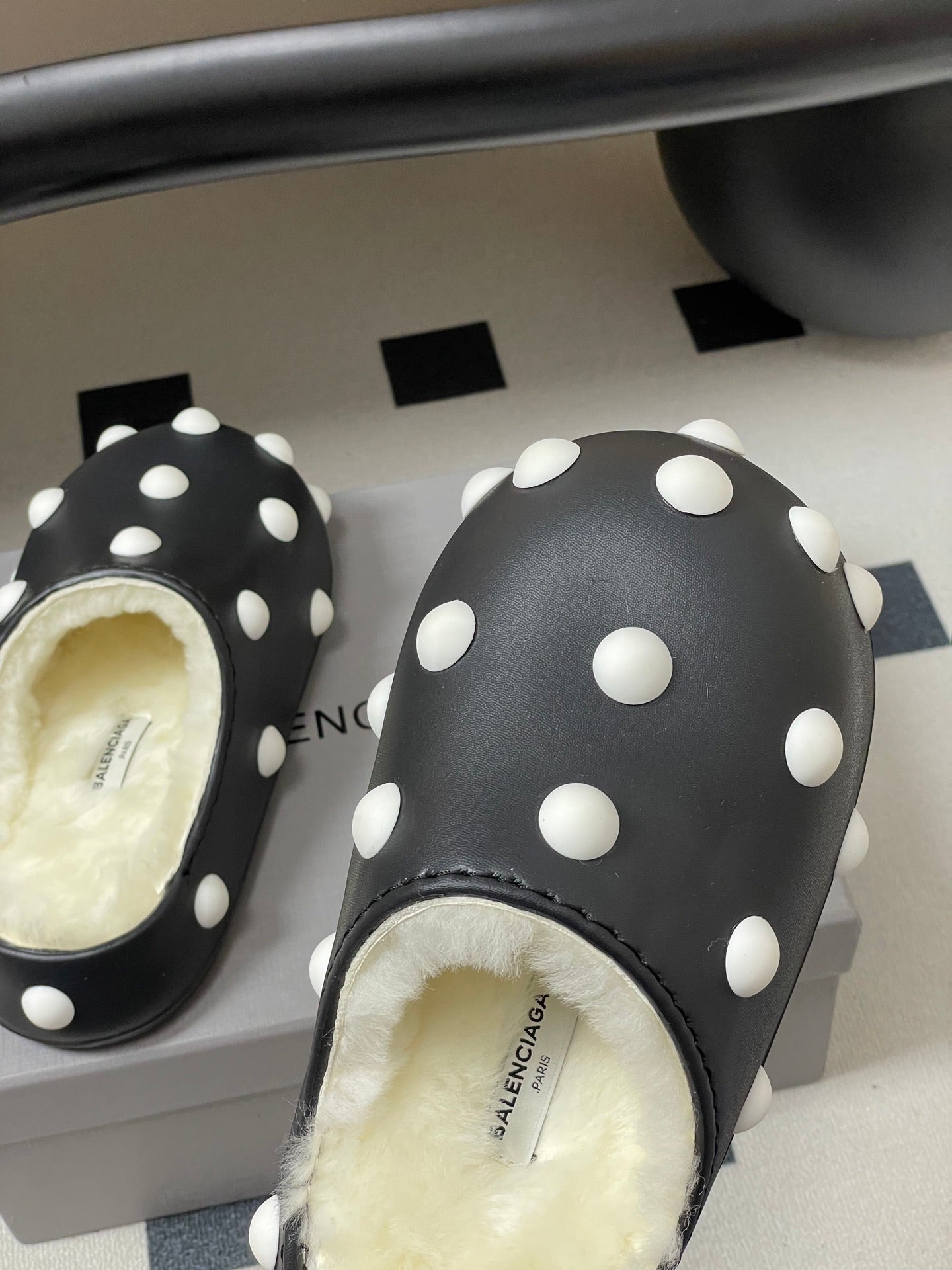 Balenciaga black polka-dot slide clogs with fuzzy lining and white dots.