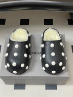 Pair of black polka-dot Balenciaga slide clogs with white dots and shearling lining.