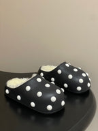 Black polka-dot slide sandals with white dots and fuzzy shearling lining.