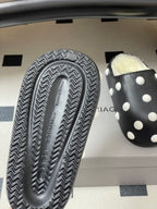 Black polka-dot slide sandal with textured zigzag outsole and shearling lining.