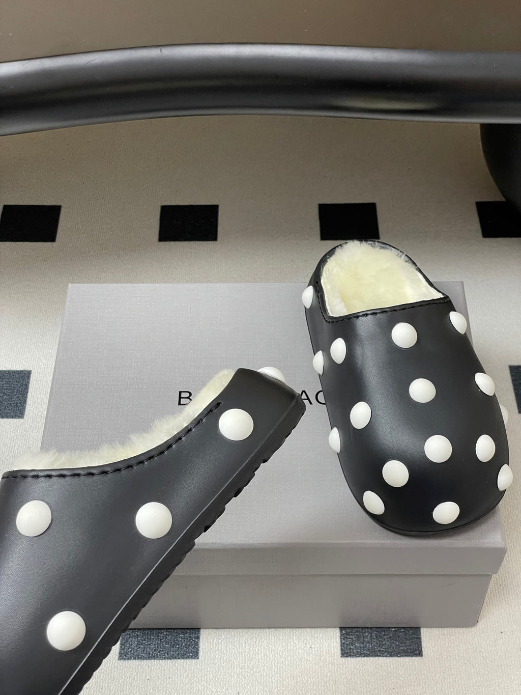 Black polka-dot slide clog with fluffy shearling lining, side view.