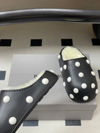 Black polka-dot slide clog with fluffy shearling lining, side view.