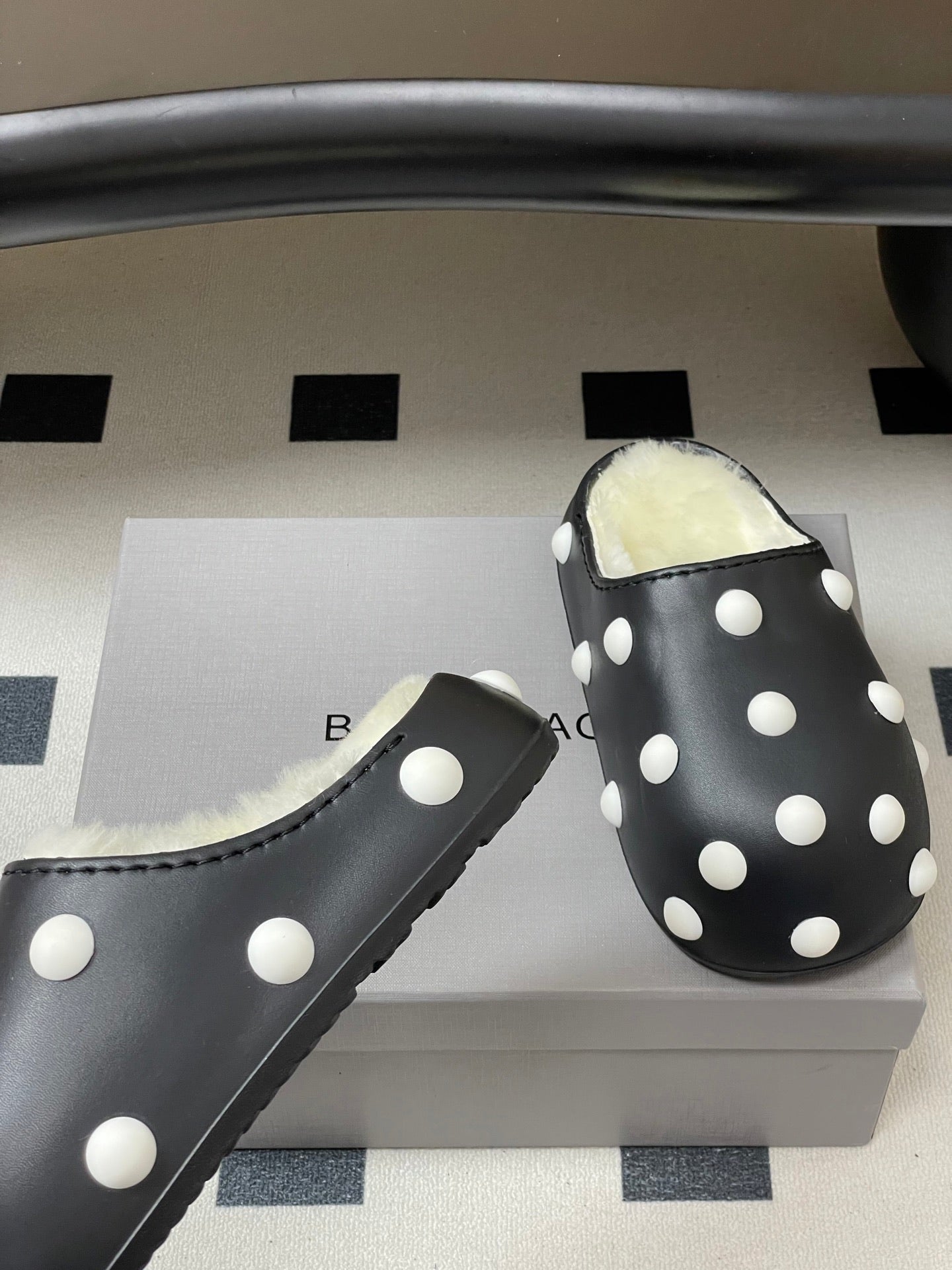 Black polka-dot slide clog with fluffy shearling lining, side view.