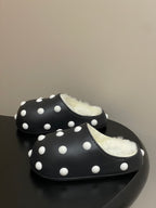 Black polka-dot slide clogs with shearling lining, side-by-side view.