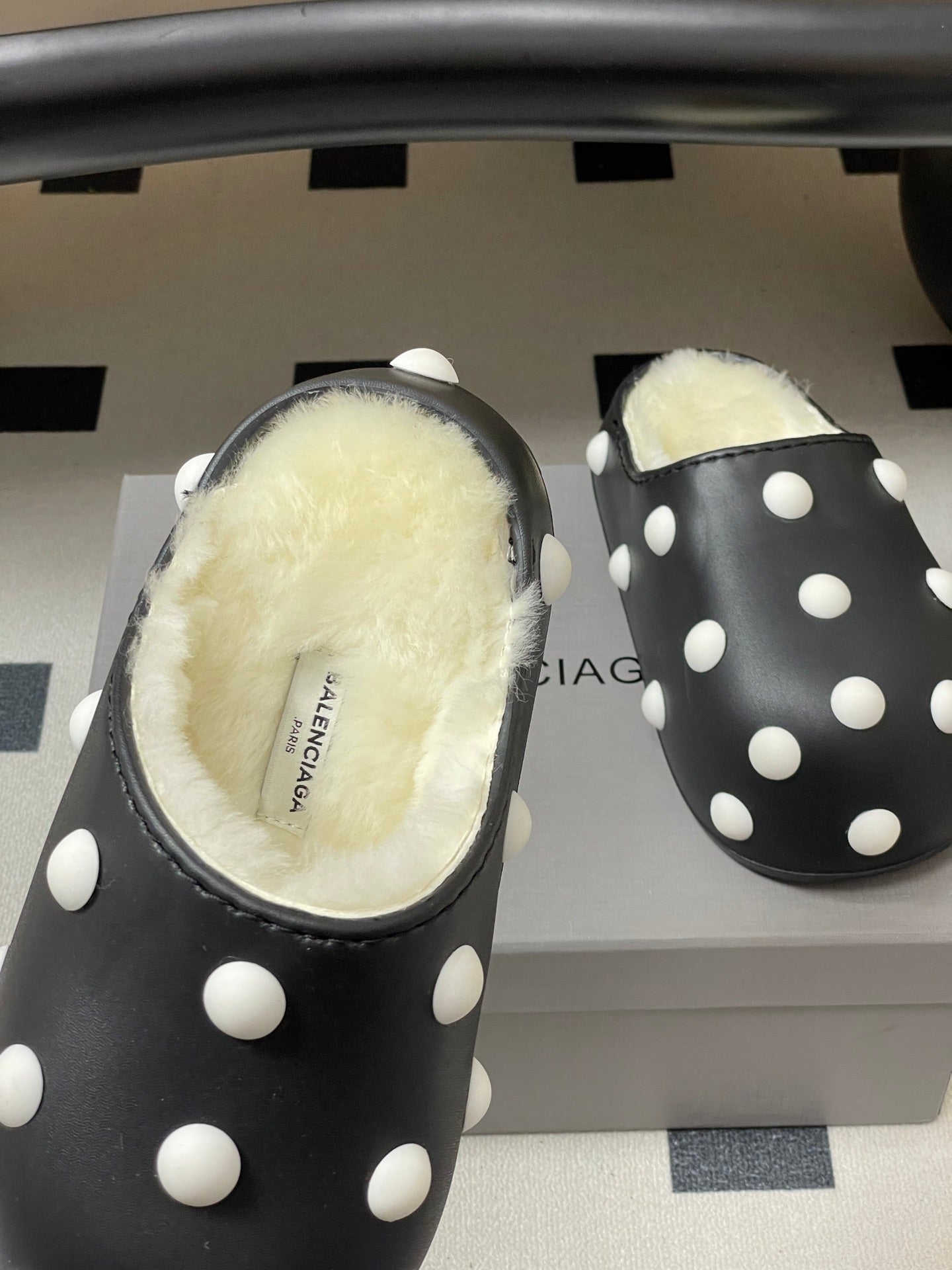Black polka-dot slide clog with shearling footbed, close-up front view.